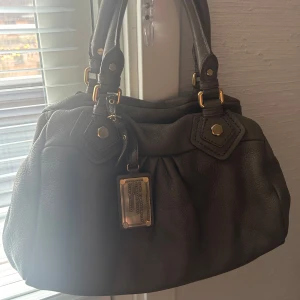 Brun baby groove väska från Marc By Marc Jacobs  - Snygg brun handväska i skinn från Marc Jacobs. Väskan har guldfärgade detaljer, och är en populär vintage modell i väldigt bra skick. Den är knappt använd och har nästan inga slitningar. 