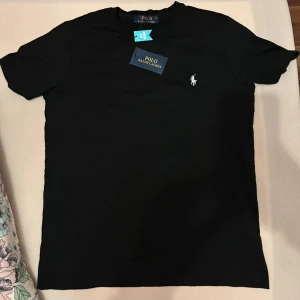 Ralph Lauren T-shirt - Snygg svart t-shirt från Ralph Lauren med klassisk passform. Perfekt för en stilren stil har aldrig använt den helt ny fick den i födelsedagspresent skick 10/10 hör av er vid frågor. Storlek M
