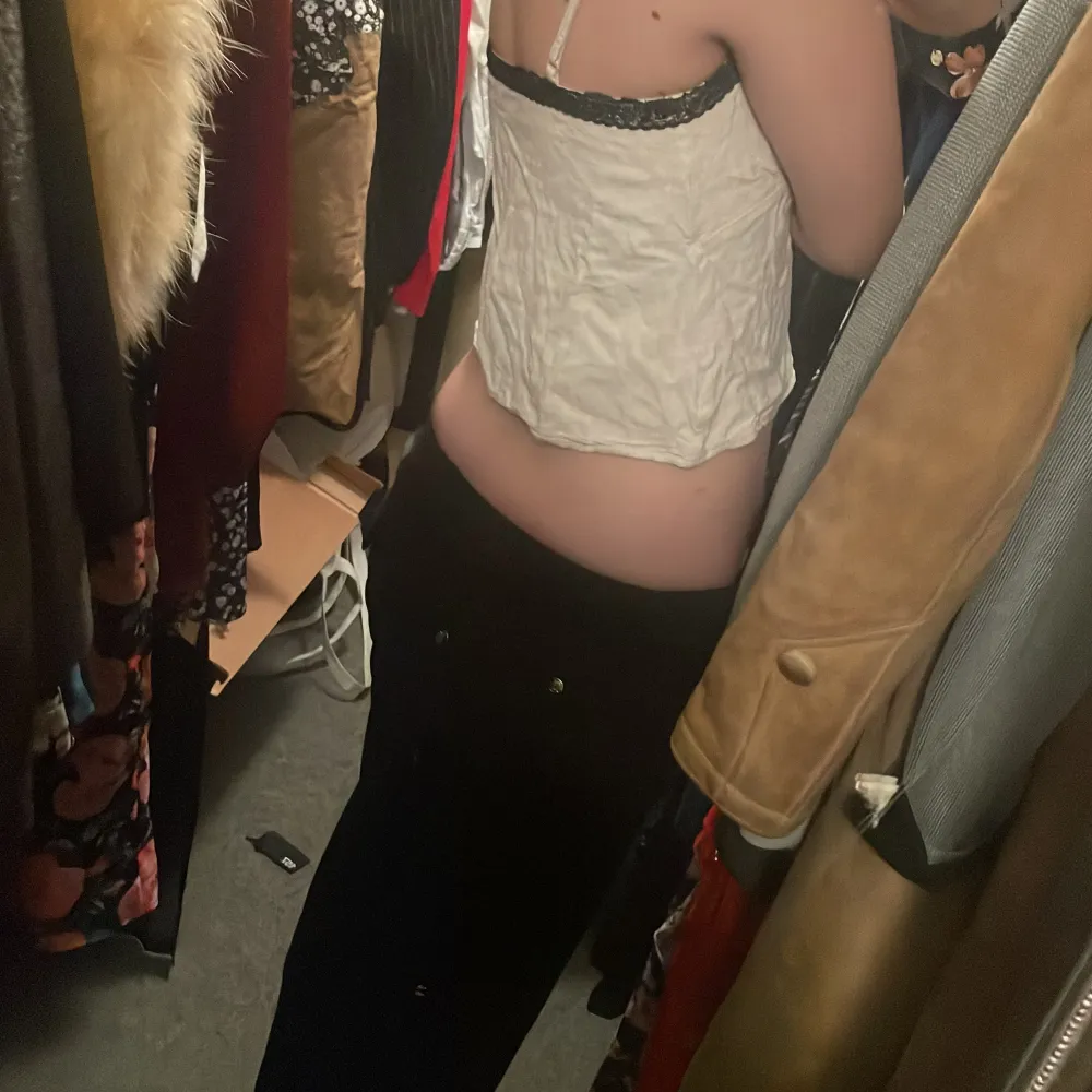 Säljer en söt beige topp från Shein med svarta spetsdetaljer vid axelbanden. Toppen är ärmlös och har en lätt croppad passform. Perfekt för varma dagar eller som ett lager under en jacka.. Yläosat.