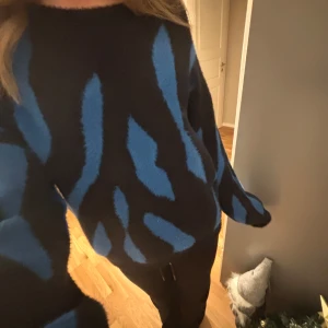 Svart och blå mönstrad tröja - Säljer en svart tröja med blått mönster. Tröjan är aldrig använd. Inga defekter.