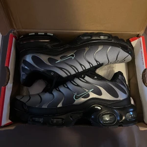 Nike Air sneakers i grått och svart - Snygga Nike tn sneakers (aldrig använd) i grått och svart med ett unikt mönster. Skorna har en synlig Air-enhet i sulan för extra komfort och en stilren design med snörning.