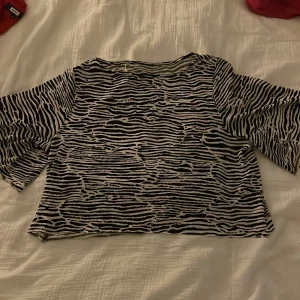 Zebramönstrad topp - Snygg zebramönstrad topp med trekvartsärm. Perfekt för att ge en djärv touch till din outfit. Den har en lös passform och är croppad för en modern look.