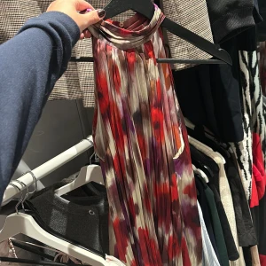 Flerfärgad blus från Mango - Säljer en snygg flerfärgad blus från Mango med ett abstrakt mönster i rött, lila och beige. Blusen är ärmlös och har en hög halsringning. Perfekt för att ge en färgklick till din garderob!