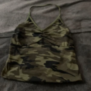 Camouflagefärgad linnetopp från Joocy Babi - Säljer en snygg camouflagefärgad linnetopp från Joocy Babi. Toppen har smala axelband och en v-ringad design. Perfekt för en avslappnad stil.