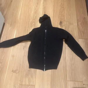 Mörkblå huvtröja med dragkedja - Säljer en stilren mörkblå huvtröja med dragkedja. Perfekt för en avslappnad look. Tröjan har långa ärmar och en bekväm passform.