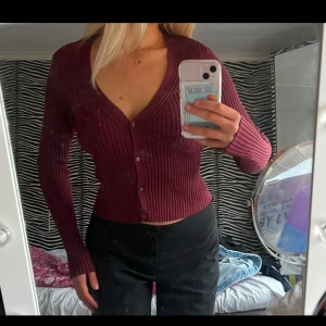 Vinröd ribbad kofta - Säljer en stilren vinröd kofta med ribbad struktur och knappar framtill. Koftan har en v-ringad design och långa ärmar, perfekt för en elegant look❤️