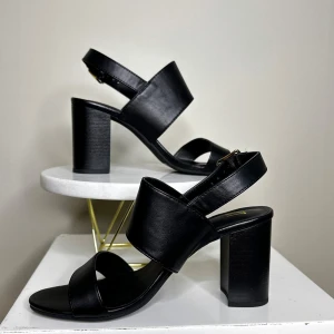 Svarta klackskor i skinn från Dinsko XIT - Snygga svarta klackskor med breda remmar och justerbart spänne från Dinsko xit. Tillverkade i skinn med en stabil blockklack som ger bra stöd. 