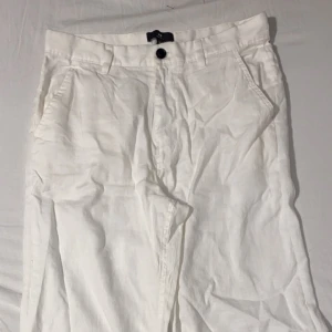 Vita linnebyxor  - Snygga vita linnebyxor med en klassisk design. De har en knapp och dragkedja framtill samt fickor både fram och bak. Perfekta för en stilren look.