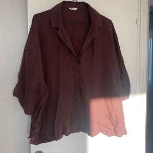 Brun oversize skjorta - Säljer en brun oversize skjorta med knappar framtill. Skjortan har en avslappnad passform och korta ärmar, perfekt för en ledig stil. Tillverkad i ett lätt och luftigt material som ger en skön känsla. Passar bra till både jeans och shorts för en avslappnad look.