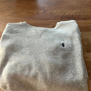 Grå tröja från Polo Ralph Lauren - Säljer en grå tröja från Polo Ralph Lauren med rund hals och broderad loga storlek-M. Passar även L | Nypris-1599.  