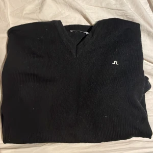 Svart tröja från J.Lindeberg - Säljer en stilren svart tröja från J.Lindeberg med en diskret logga på bröstet. Tröjan har en v-ringad hals och är perfekt för en minimalistisk look. Storlek M men är betydligt mindre i storleken, mvh luxury 