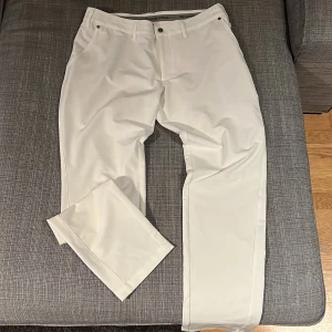 Vita golfbyxor  - Snygga vita golfbyxor med en klassisk passform. De har en midwaist design och stängs med dragkedja och knappar. Perfekta för en stilren look på golfbanan. Nypris 1250