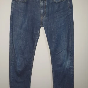 Blå jeans från Dressmann - Snygga blå jeans från Dressmann i regular fit. Klassisk design med fem fickor och knappgylf. Perfekta för en avslappnad stil.
