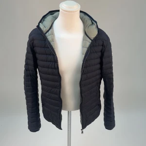 Marinblå pufferjacka från Colmar - Snygg marinblå pufferjacka från Colmar med huva och dragkedja. Jackan har en quiltad design och är perfekt för kyligare dagar. Lätt att matcha med olika outfits.