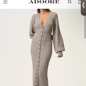 Beige klänning ADOORE- slutsåld - BYTER GÄRNA MOT 34!!! HELT NY, onvänd. Snygg beige ribbad långklänning från ADOORE med knappar hela vägen ner. Klänningen har en v-ringad design och långa ärmar som ger en elegant look. Perfekt för kyligare dagar när du vill vara både bekväm och stilren.