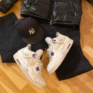 Jordan 4 metallic purple - Snygga Nike Air Jordans i vitt med lila detaljer. Skorna har klassisk snörning och en ikonisk Jumpman-logga på tungan och hälen. Perfekta för dig som vill ha en stilren och sportig look.