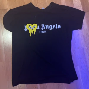 Svart t-shirt   - Säljer en svart t-shirt med ett gult hjärta och texten 'London' på framsidan. T-shirten har korta ärmar och en normal passform. Perfekt för en avslappnad stil.