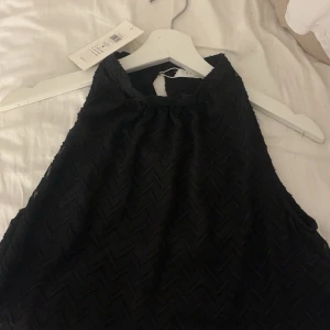 Svart ärmlös topp från Vila - Säljer en stilren svart ärmlös topp från Vila. Toppen har ett subtilt mönster och en elegant design som passar perfekt för olika tillfällen. Den är tillverkad i ett mjukt material och har en bekväm passform.