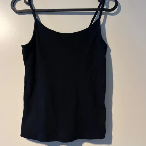 Svart ribbad linnetopp från FB Sister - Säljer en stilren svart ribbad linnetopp från FB Sister i storlek S. Perfekt för sommardagar eller som ett basplagg i garderoben. Toppen har smala axelband och en bekväm passform. Passar både till vardags och fest! 🖤