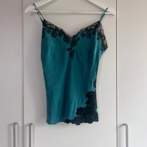 Topp  - Grön/blå topp med lite spets detaljer köpt på secondhand, storlek 36/38? Banden går att spänna in! 
