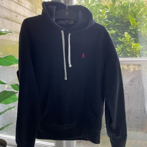 Svart hoodie från Polo Ralph Lauren - Säljer en klassisk svart hoodie från Polo Ralph Lauren. Den är helt ny i materialet använd någon gång men syns inte alls. Säljer då jag inte använder den! Perfekt för en avslappnad stil och passar till det mesta. Superbekväm och i bra skick!