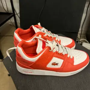 Snygga Lacoste sneakers i orange färg. Perfekt för vardagligt bruk eller för att addera en touch av stil till din outfit. Använda 1 gång inomhus. Nästintill sprillans nya i skick.  Nypris cirka 1300 kr! :)  Spana in min profil för fler skor kläder et