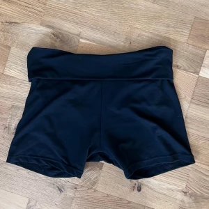 Svarta shorts - Säljer ett par svarta shorts i stretchigt material. Perfekta för träning eller en avslappnad dag. De har en bred midja för extra komfort och en tight passform som sitter bra på kroppen. Passar perfekt för sommarens alla aktiviteter! Lågmidjade med kant man kan vika ner