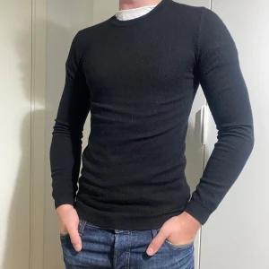 Svart merinoull tröja - Säljer en stilren svart långärmad tröja i slim fit. Perfekt för både vardag och fest. Tröjan är i bra skick och passar utmärkt till ett par jeans. Ett måste i garderoben för en klassisk look!