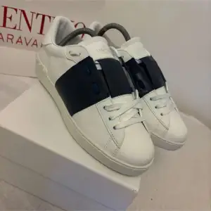 Säljer ett par snygga Valentino Open sneakers i vitt med svarta detaljer. Skorna är i nytt skick och kommer med originalförpackning och dustbag. Perfekta för både vardag och fest! Storlek och passform är normal.