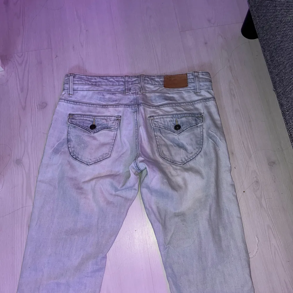 Säljer ett par ljusa jeans i bra skick med coola slitningar. De har en straight passform skulle jag säga. Lågmidjade och trendiga bakfickor! Är osäker på märke! Skulle säga storlek.  S/M Midjemåttet tvärs över är ca 42cm och innerbenslängden är ca 82 från grenen och ner!. Jeans & Byxor.