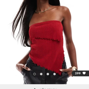 Röd tubtopp - Snygg röd tubtopp i ett ribbat material med asymmetrisk kant. Perfekt för en utekväll eller fest. Toppen är ärmlös och har en tight passform som framhäver figuren.