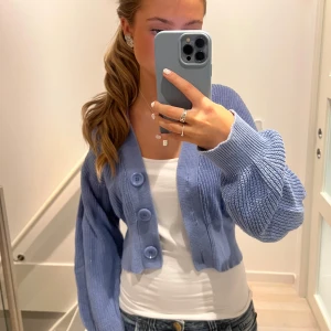 Blå stickad kofta - Säljer en superfin blå stickad kofta med stora knappar framtill. Den är croppad och har en skön, lös passform. Perfekt för både vår och höst! 🦋