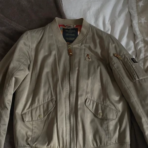Beige bomberjacka från Morris - Säljer en snygg beige bomberjacka från Morris i storlek medium. Jackan har en dragkedja framtill och en praktisk ficka med dragkedja på ärmen. Den är i mycket bra skick och perfekt för höst och vår. Passar både till vardags och lite finare tillfällen. 🧥✨