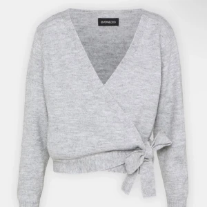 Grå omlottkofta från Even&Odd - Säljer en superfin grå omlottkofta från Even&Odd. Den är stickad och har en snygg knytning i sidan. Perfekt för höst och vinter, och den är i helt nytt skick. Koftan har långa ärmar och en mysig passform. Helt oanvänd! Råkade köpa 2 st! Passar som M!