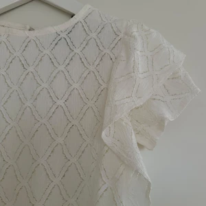 Vit spetstopp  - Säljer min helt oanvända vita spetstopp från Holly & White med volangdetaljer på ärmarna. Strlk XS. Lapp finns kvar.