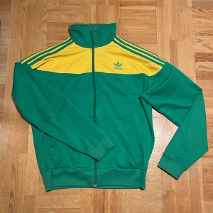 Adidas zip - RIKTIGT fet adidas zip i gult och grönt. Oregon färgtema. Helt felfri utom lite slitage på texten över ryggen. Storlek L enligt etiketten men skulle säga att den sitter M. Fråga gärna om mått eller fler bilder!!!
