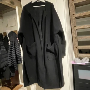 Svart kappa från Zink - Snygg svart kappa från Zink med en stilren design. Den har långa ärmar och praktiska fickor framtill. Perfekt för kyligare dagar och ger en elegant look. 🖤Stl XL, väl använd men i gott skick🫶🏼