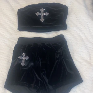 Svart sammet sett med korsdetaljer - Trendig svart sett i mjukt sammetstyg med glittrande korsdetaljer på både överdel och underdel. Bandeau-toppen och de höga midjebyxorna ger en stilren look. 