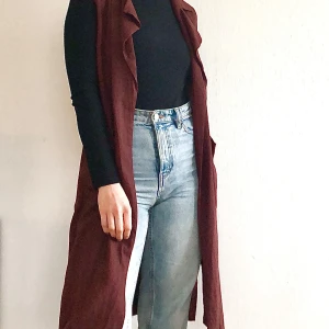 Vinröd väst från Lindex - Snygg vinröd väst från Lindex i en längre modell. Västen har en knytning i midjan och är perfekt för lager-på-lager-stil. Den är ärmlös och har en stilren design som passar till många olika outfits. Storlek S men tycker den passar till en M utan problem.  (Finns på fler säljsidor)