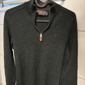 Halfzip från Morris - Säljer en stilren mörkgrön tröja från Morris i 100% merinoull. Tröjan har en dragkedja vid halsen och ett diskret broderat emblem på bröstet. Säljs då den är för liten. Pris går att diskutera!
