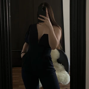 Jumpsuit  - Snygg svart oneshoulder jumpsuit med djup v-ringning. Perfekt för en stilren look. Den har en tight passform som framhäver figuren.🥰🥰🥰