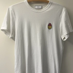 AMI T-Shirt - Soft vit AMI-smiley T-Shirt. Väldigt clean och skön att ha på sig. Inga defekter alls. Strl S.