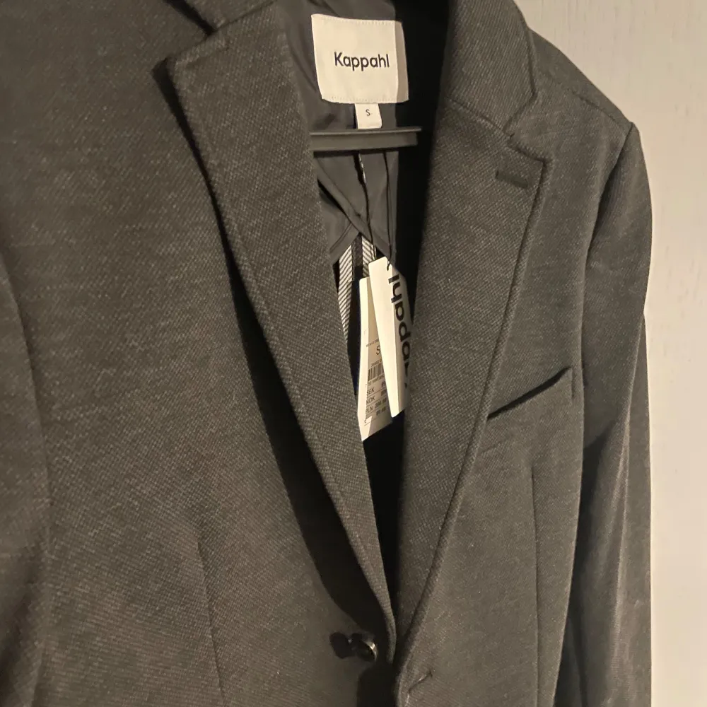 Snygg grå kavaj från Kappahl i storlek S. Kavajen har en klassisk design med knappar framtill och fickor. Perfekt för en stilren look. Aldrig använd pga av för stor för mig. Så i nyskick! Nypris 999. Puvut & Bleiserit.