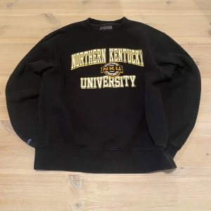 Collagetröja Champion - Säljer en svart sweatshirt från Champion från Northern Kentucky University i gult och vitt. Perfekt för en avslappnad stil. Skriv för frågor och mått osv