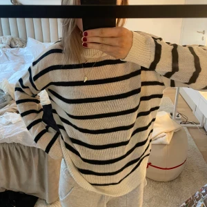 Randig stickad tröja - Fin stickad tröja med svarta ränder. Perfekt för sommar kvällar och våren! Fåtal defekter.