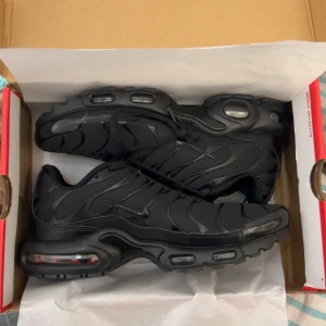Nike Tns  - Snygga svarta Nike sneakers med en robust sula och klassisk snörning. Skorna har en sportig design med synliga luftkuddar i sulan för extra komfort. Perfekta för en stilren look. Nya använda 3 gånger väldigt försiktigt går du med de ute märker man inte att de är använda 