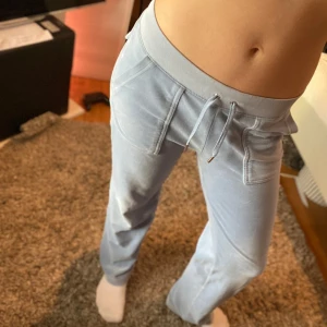 Ljusblå mjukisbyxor från Juicy Couture - Snygga ljusblå mjukisbyxor från Juicy Couture med snörning i midjan och bakficka med knappar. Perfekta för en avslappnad stil. Supermjukt material som känns skönt mot huden.Priset är förhandlingsbart❤️🥰