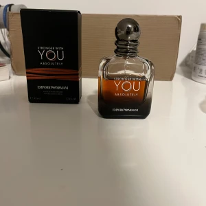 Stronger With You Absolutely från Emporio Armani - Säljer en elegant parfym, Stronger With You Absolutely, från Emporio Armani. Flaskan är stilrent designad i mörkt glas med en metallisk kork. Doften är intensiv och maskulin, perfekt för den som vill sticka ut. Flaskan rymmer 50 ml.