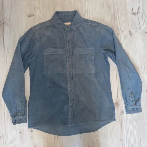 Blå manchester overshirt från Revolution - Säljer en stilren blå manchester overshirt från Revolution. Perfekt för en avslappnad look. Köpt i Åre för 900 kr. Nyskcik utan prislapp då den bara är använd 2 gånger, då den är för stor för mig. Stolken är mer som L, än M som står i skjortan. Köparen står för frakten📦
