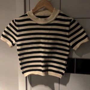 Randig stickad tröja - Säljer en snygg randig stickad tröja i svart och vit. Tröjan har korta ärmar och en rund halsringning. Passar bra till både jeans och kjol.